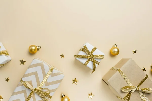 Hediye kutuları, altın süsler ve pastel bej arka planda süsler. Noel arkaplanı. Düz konum, üst görünüm, kopyalama alanı.