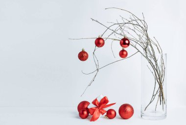 Kırmızı süslemelerle süslenmiş vazoda ağaç brandaları. Minimalist Noel kompozisyonu. Beyaz arkaplan.