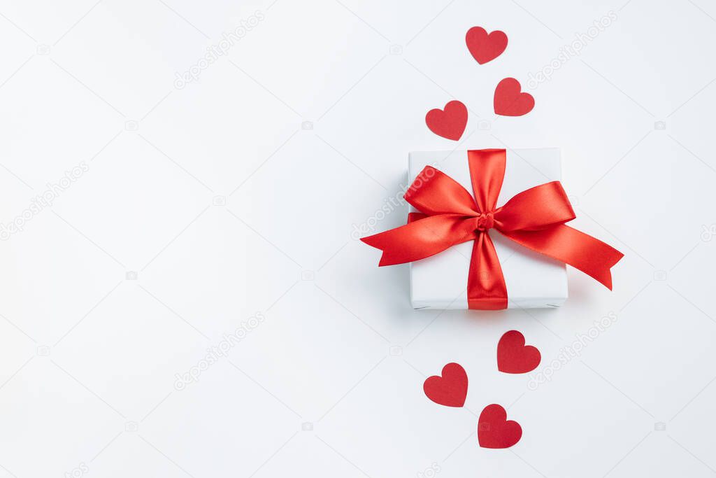 Gift box with red ribbon and hearts on white background. Valentines day banner with free space. Top view, flat lay.