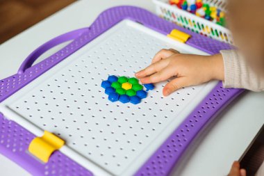 Çocuk evde mozaik bulmacalarla oynuyor. Erken gelişim ve iyi motor beceriler için çocukların yaratıcı oyunu.