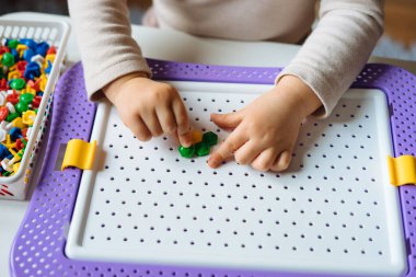 Çocuk evde mozaik bulmacalarla oynuyor. Erken gelişim ve iyi motor beceriler için çocukların yaratıcı oyunu.