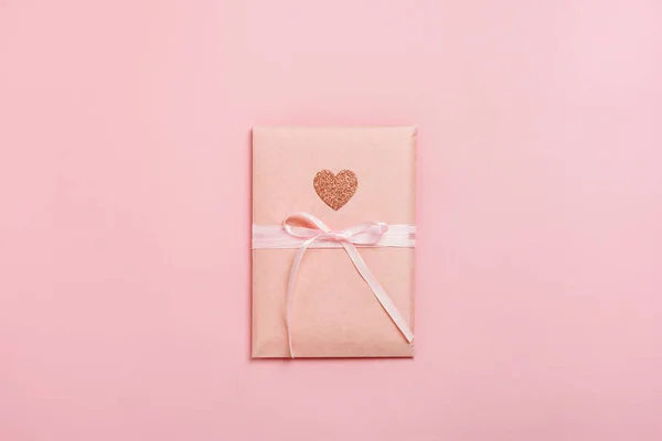 Pastel pembe arka planda kalbi olan hediye paketi. Sevgililer Günü kompozisyonu. Üst manzara, düz uzanma.
