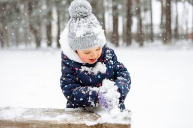 Şirin küçük kız dışarıda karla oynarken eğleniyor. Karlı kış havası.