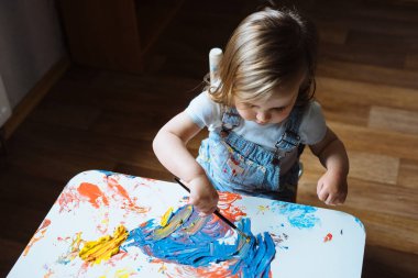 Evde, masanın üzerinde fırçayla çocuk resmi.