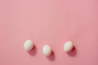 Pembe arka planda beyaz yumurtalar.