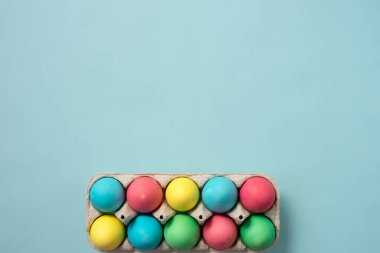Pastel mavi arka planda renkli paskalya yumurtası tepsisi. Kopyalama alanı olan düz.