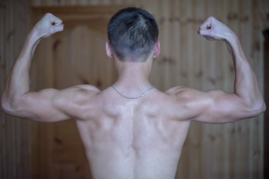 Yakışıklı kaslı vücut geliştirmeci gri arka plan üzerinde poz. Düşük anahtar studio vurdu. Seksi erkek vücut