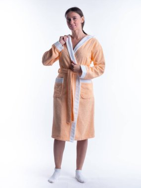 Yüzünde bir gülümseme olan, izole beyaz arka planda, bornozlu bir kadın. Stüdyoda tam gelişimle çekilmiştir..