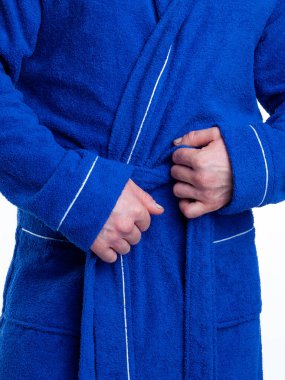 Parlak, banyo cüppeli bir adam beyaz bir arka planda kıyafet reklamları yapıyor. Stüdyoda yakın çekim..