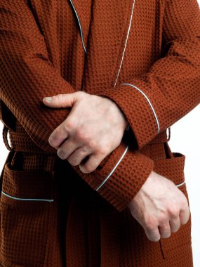 Parlak, banyo cüppeli bir adam beyaz bir arka planda kıyafet reklamları yapıyor. Stüdyoda yakın çekim..