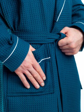 Parlak, banyo cüppeli bir adam beyaz bir arka planda kıyafet reklamları yapıyor. Stüdyoda yakın çekim..