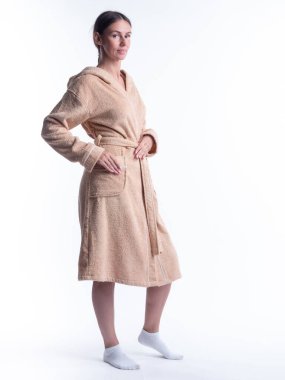 Yüzünde bir gülümseme olan, izole beyaz arka planda, bornozlu bir kadın. Stüdyoda tam gelişimle çekilmiştir..