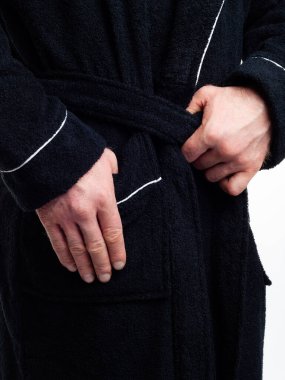 Parlak, banyo cüppeli bir adam beyaz bir arka planda kıyafet reklamları yapıyor. Stüdyoda yakın çekim..