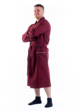 Yüzünde bir gülümseme olan beyaz bir arka planda, bornozlu güçlü bir adam. Stüdyoda tam gelişimle çekilmiştir..