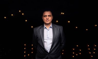 Takım elbiseli yakışıklı iş adamı kameraya bakıyor. Siyah arkaplanda izole edilmiş