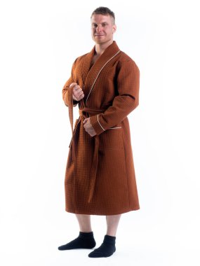 Yüzünde bir gülümseme olan beyaz bir arka planda, bornozlu güçlü bir adam. Stüdyoda tam gelişimle çekilmiştir..