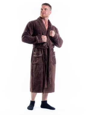 Yüzünde bir gülümseme olan beyaz bir arka planda, bornozlu güçlü bir adam. Stüdyoda tam gelişimle çekilmiştir..