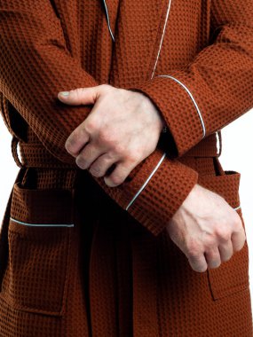 Parlak, banyo cüppeli bir adam beyaz bir arka planda kıyafet reklamları yapıyor. Stüdyoda yakın çekim..