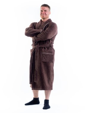 Yüzünde bir gülümseme olan beyaz bir arka planda, bornozlu güçlü bir adam. Stüdyoda tam gelişimle çekilmiştir..