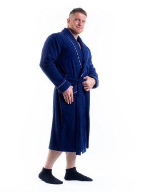 Yüzünde bir gülümseme olan beyaz bir arka planda, bornozlu güçlü bir adam. Stüdyoda tam gelişimle çekilmiştir..