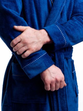 Parlak, banyo cüppeli bir adam beyaz bir arka planda kıyafet reklamları yapıyor. Stüdyoda yakın çekim..