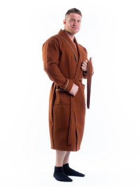 Yüzünde bir gülümseme olan beyaz bir arka planda, bornozlu güçlü bir adam. Stüdyoda tam gelişimle çekilmiştir..