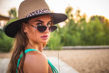 Yeşil mayo, siyah bardaklar ve kameranın önünde poz veren güzel bir esmer manken. Yakın çekim ve uzun menzilli çekim.