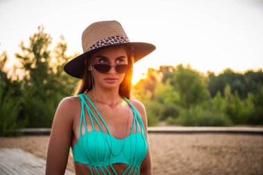 Yeşil mayo, siyah bardaklar ve kameranın önünde poz veren güzel bir esmer manken. Yakın çekim ve uzun menzilli çekim.