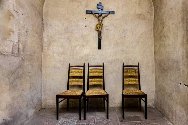 Tahta bir haçın altında terk edilmiş üç sandalye.