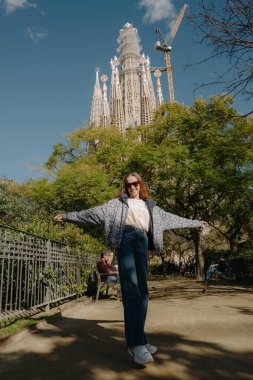 Barcelona 'da Sagrada Familia yakınlarında dönen ve gülümseyen genç bir kadın.