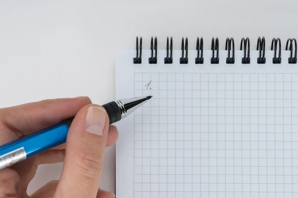 La mano sta scrivendo sul taccuino della pagina bianca su sfondo bianco Foto Stock