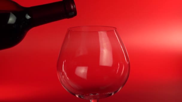 Чоловіча рука виливає червоне вино в склянку з пляшки крупним планом. Чоловік поливає червоне вино — стокове відео