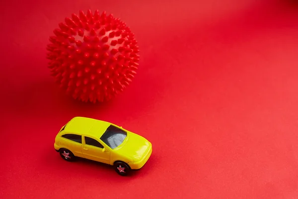 yellow toy car on red background with coronavirus model, concept idea of taxi and cargo delivery during quarantine.