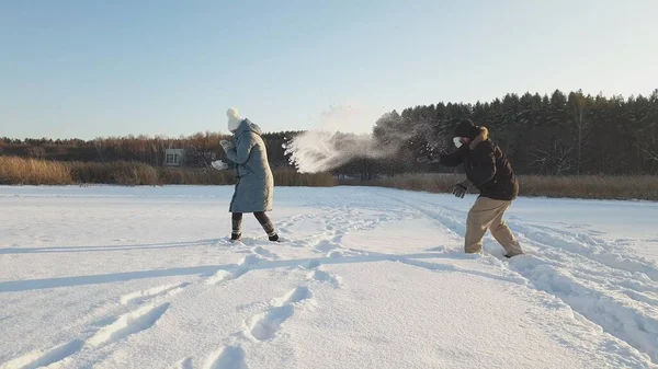 a woman and a man in medical masks play snowballs in a winter park, wearing a medical mask in public places helps prevent the development of the coronavirus epidemic.