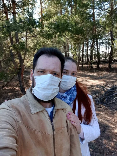 a couple in love in a medical mask takes a selfie on a smartphone.