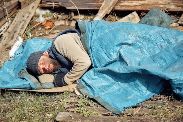 a homeless man near the ruins sleeps on cardboard boxes, helping poor and hungry people during the epidemic.