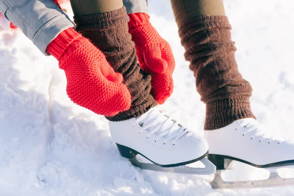 Menina em patins vestido mitenes amarrando cadarços — Fotografia de Stock