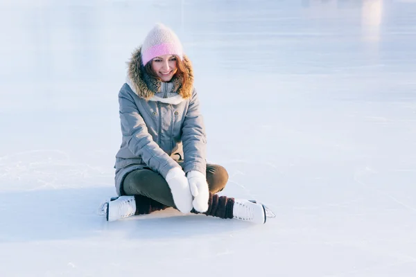 Ice skating woman sitting on the ice smiling — Stock Photo, Image
