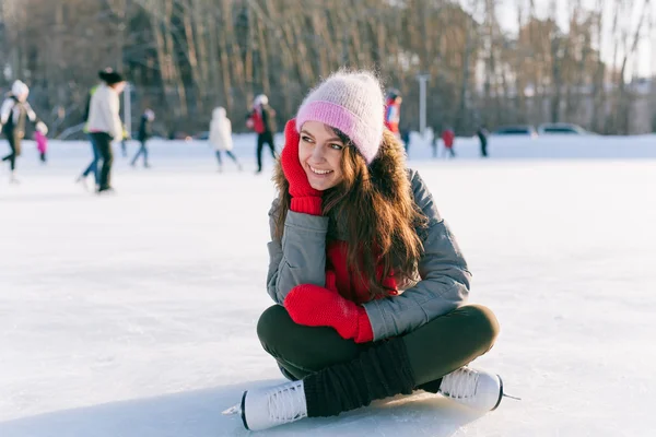 Ice skating woman sitting on the ice smiling — Stock Photo, Image