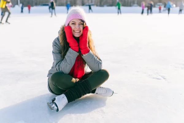 Femme patinoire assise sur la glace souriant — Photo