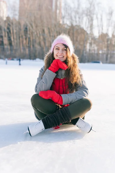 Ice skating woman sitting on the ice smiling — Stock Photo, Image