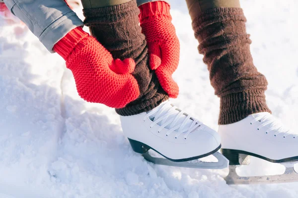 Menina em patins vestido mitenes amarrando cadarços — Fotografia de Stock