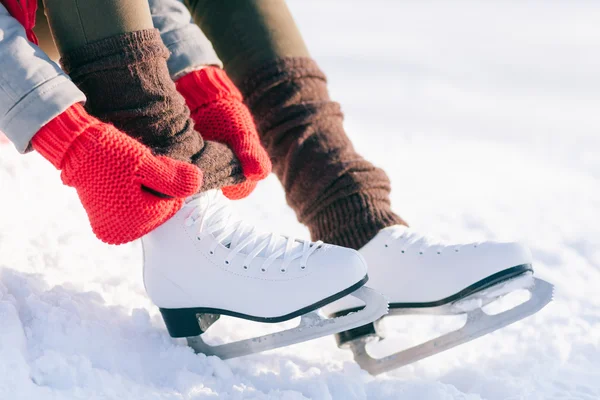 Girl in dress skates mittens tying shoelaces Royalty Free Stock Photos