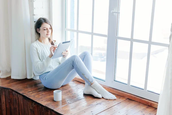 Unga vackra långa hår kvinna med hjälp av tablet PC inomhus. — Stockfoto