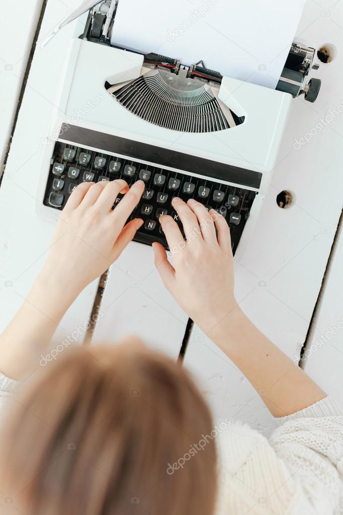 womans hand typing on retro machine
