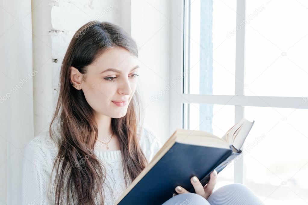 Young woman at home reading book