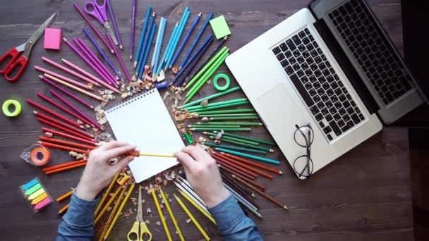 Рабочее место с цветными карандашами, ноутбуком, палитрой на деревянном столе — стоковое видео