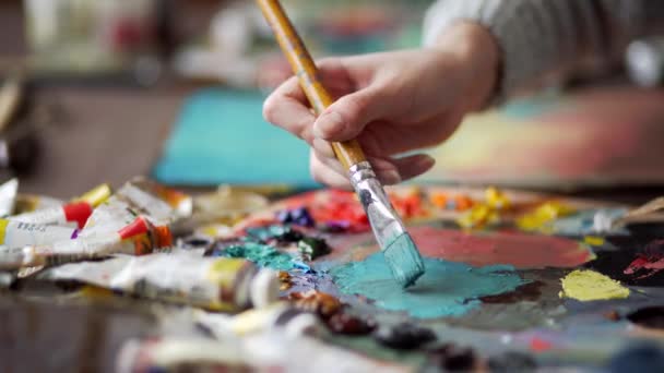 Primer plano del pincel en las manos de la mujer mezclando pinturas en la paleta — Vídeos de Stock