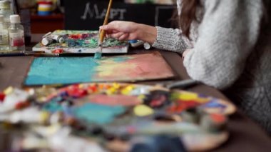 Ressam, boya fırçasının resmini palet kaplamalı olarak çiziyor..