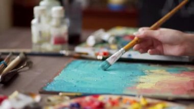 Ressam, boya fırçasının resmini palet kaplamalı olarak çiziyor..